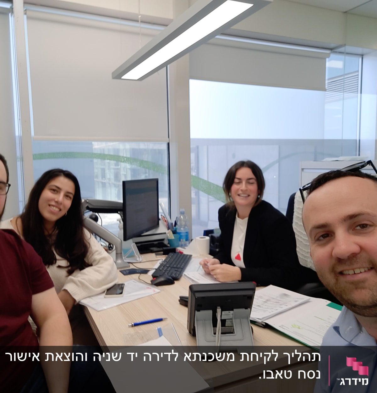 אנשים יושבים ליד שולחן עם מחשב ומסמכים